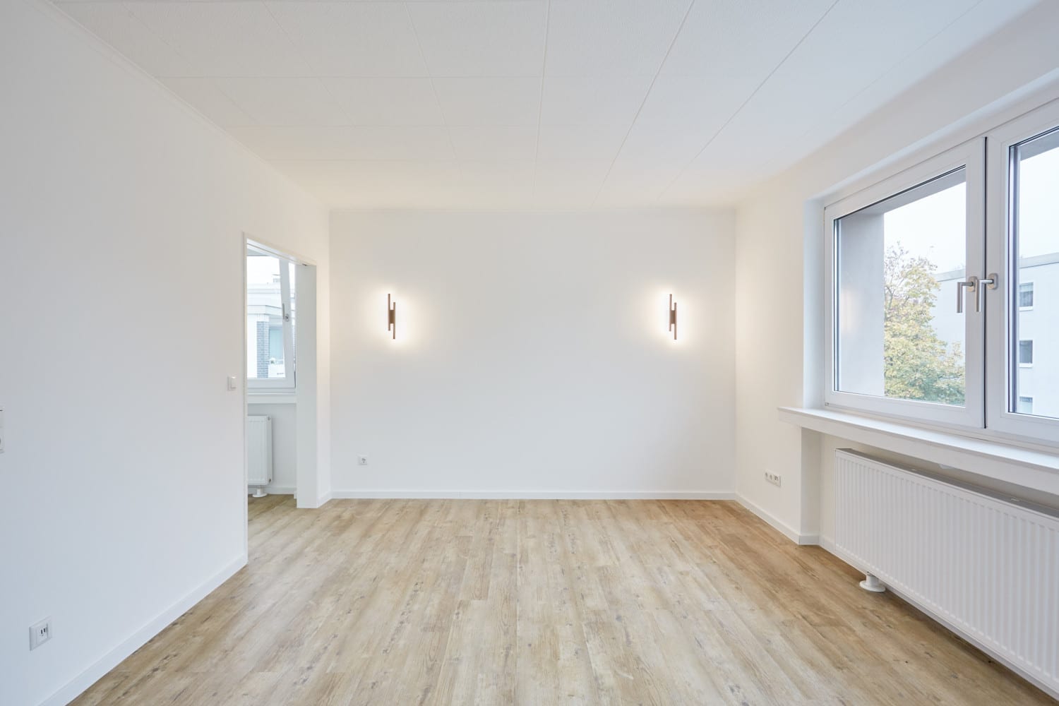 Wohnbereich mit Fenster und schlanken Wandleuchten