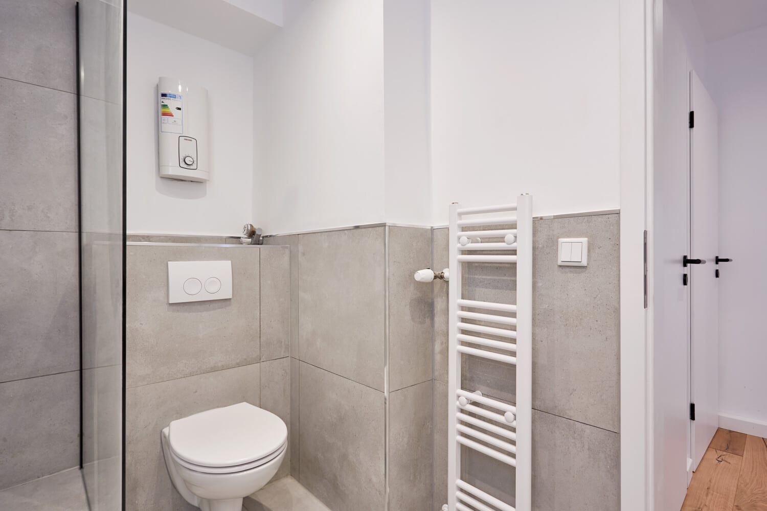 Badezimmer mit grauen Fliesen und Handtuchheizkörper