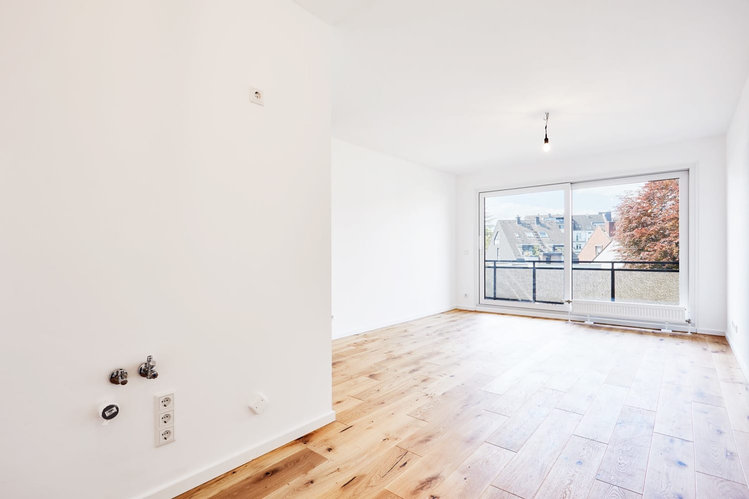 Wohnraum mit Fensterfront und Zugang zum Balkon