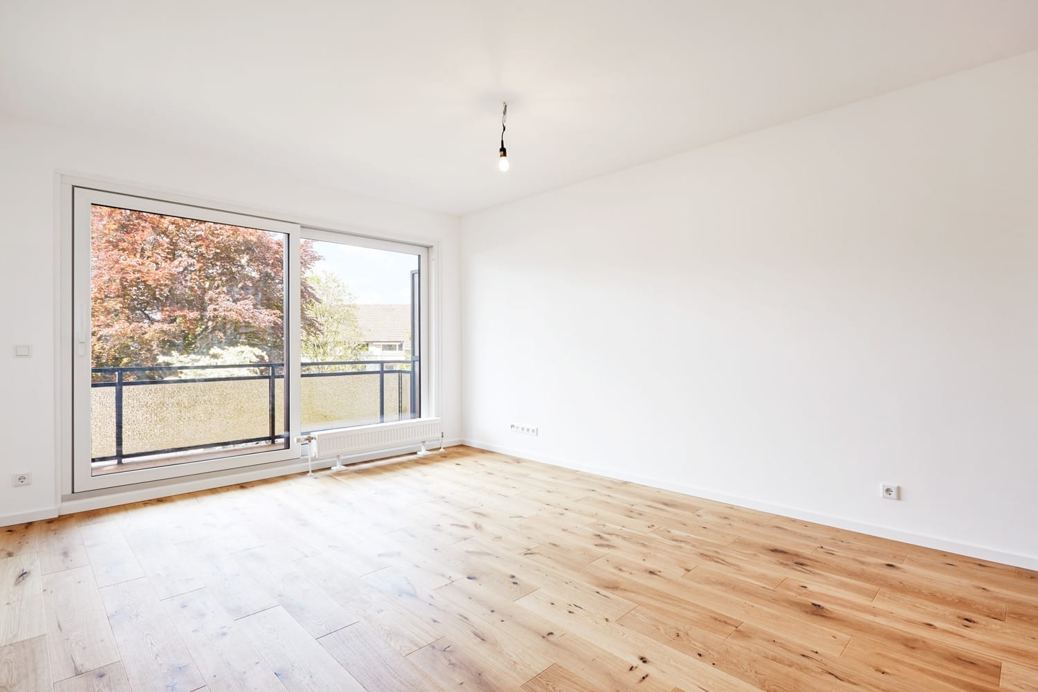 Wohnraum mit breitem Fenster und heller Eichendiele