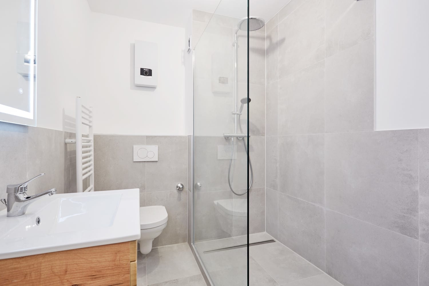 Badezimmer mit Glasdusche und grauen Großformatfliesen