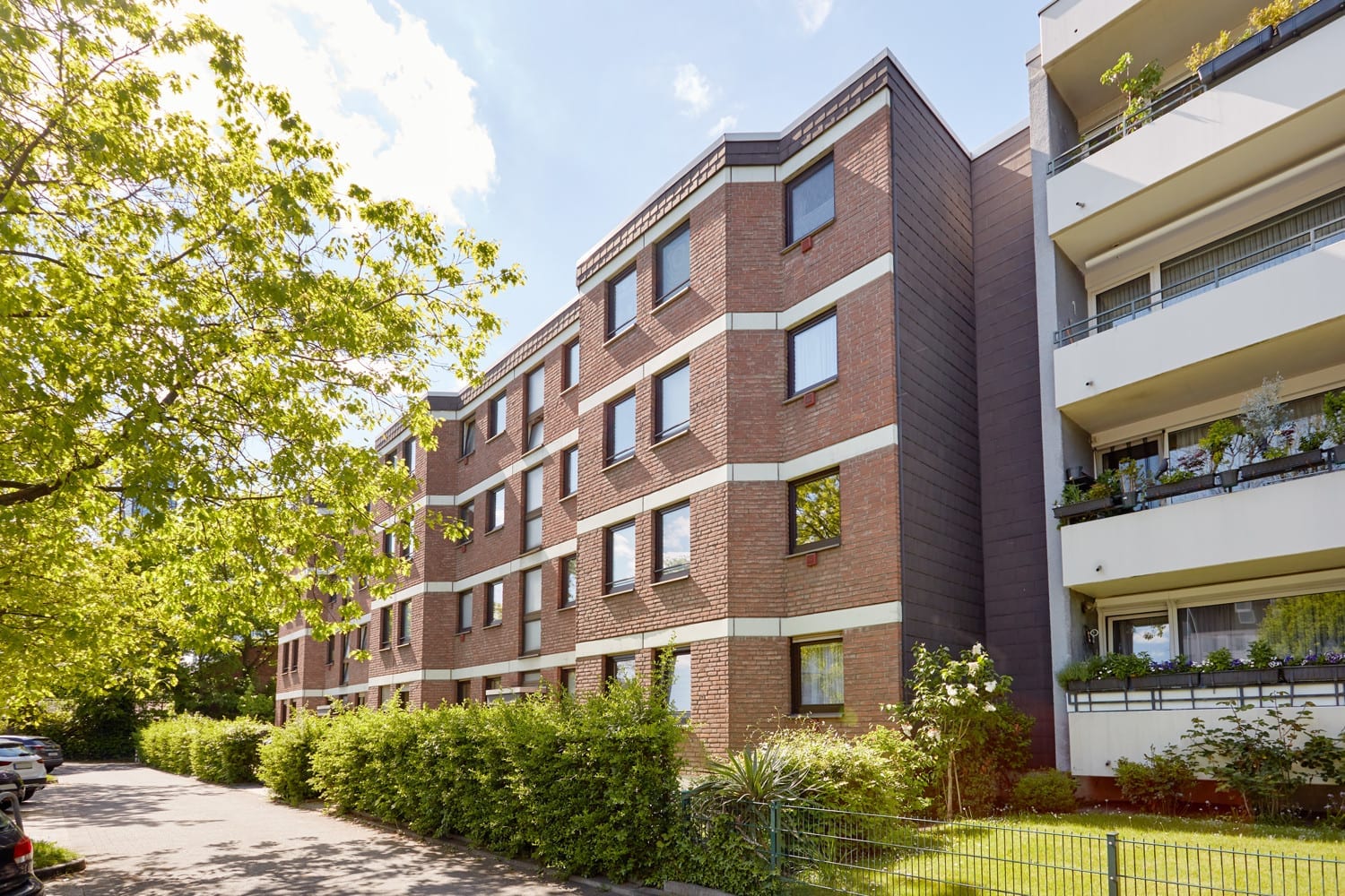 Wohnhaus mit Klinkerfassade, Balkonen und altem Baumbestand